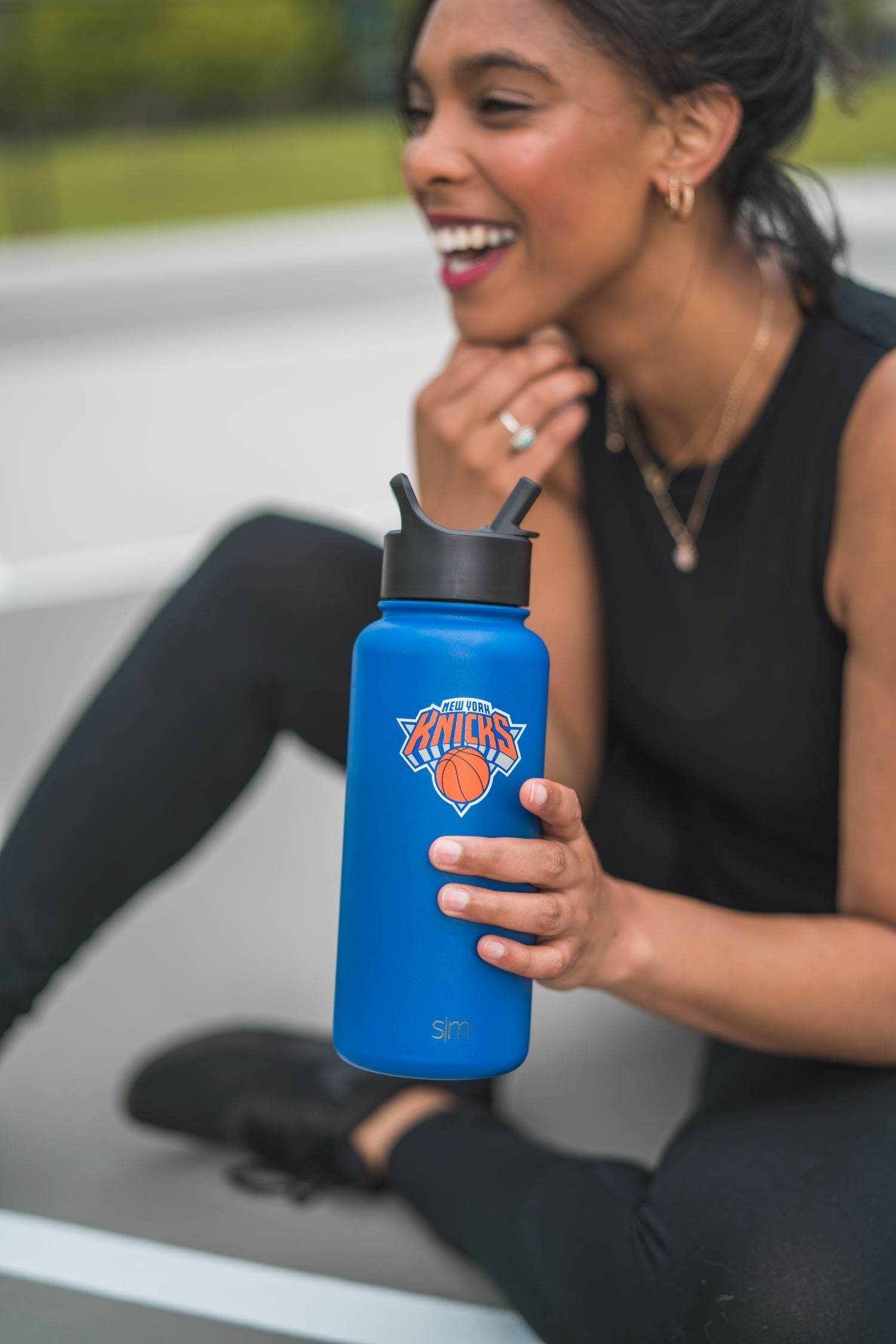Woman in outdoor setting holding a bright royal blue water bottle