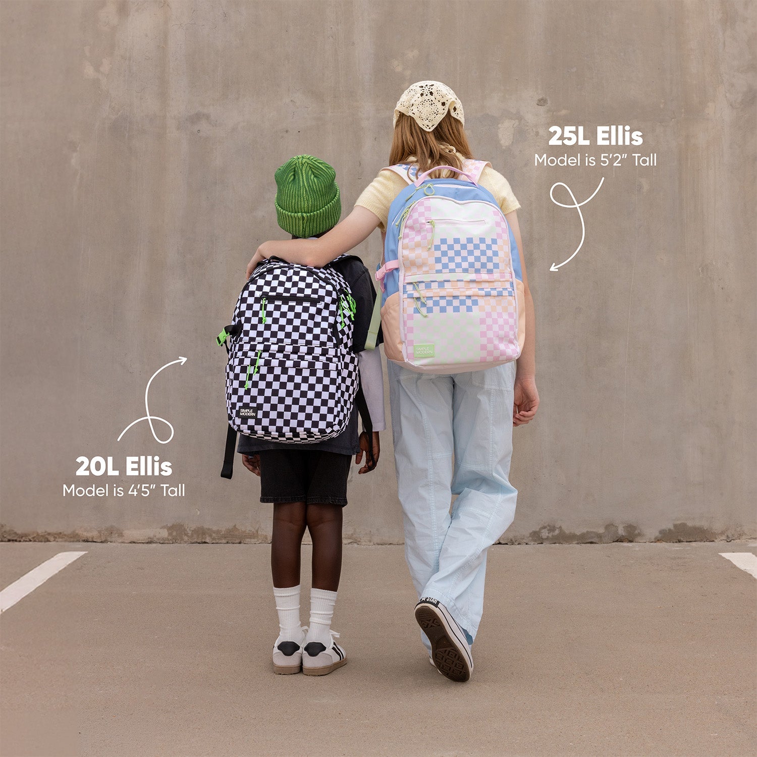 Two models standing back-to-back wearing Simple Modern Ellis backpacks: 4'5" model on left with 20L black and white checkerboard backpack with green accents; 5'2" model on right with 25L pastel pink and blue backpack. Size