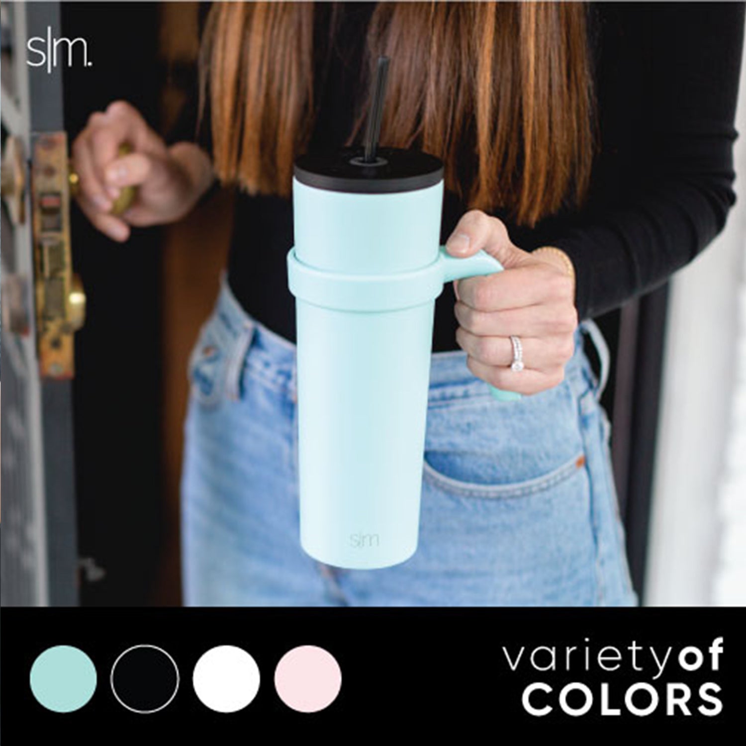 Light blue ceramic mug with classic handle held by person wearing black clothing against warm brown background
