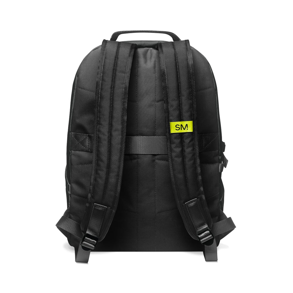 Black backpack with neon yellow brand patch, shown from rear view. Features padded shoulder straps, top handle, front zippered pockets, and gray webbing detail. Studio product shot on white background.