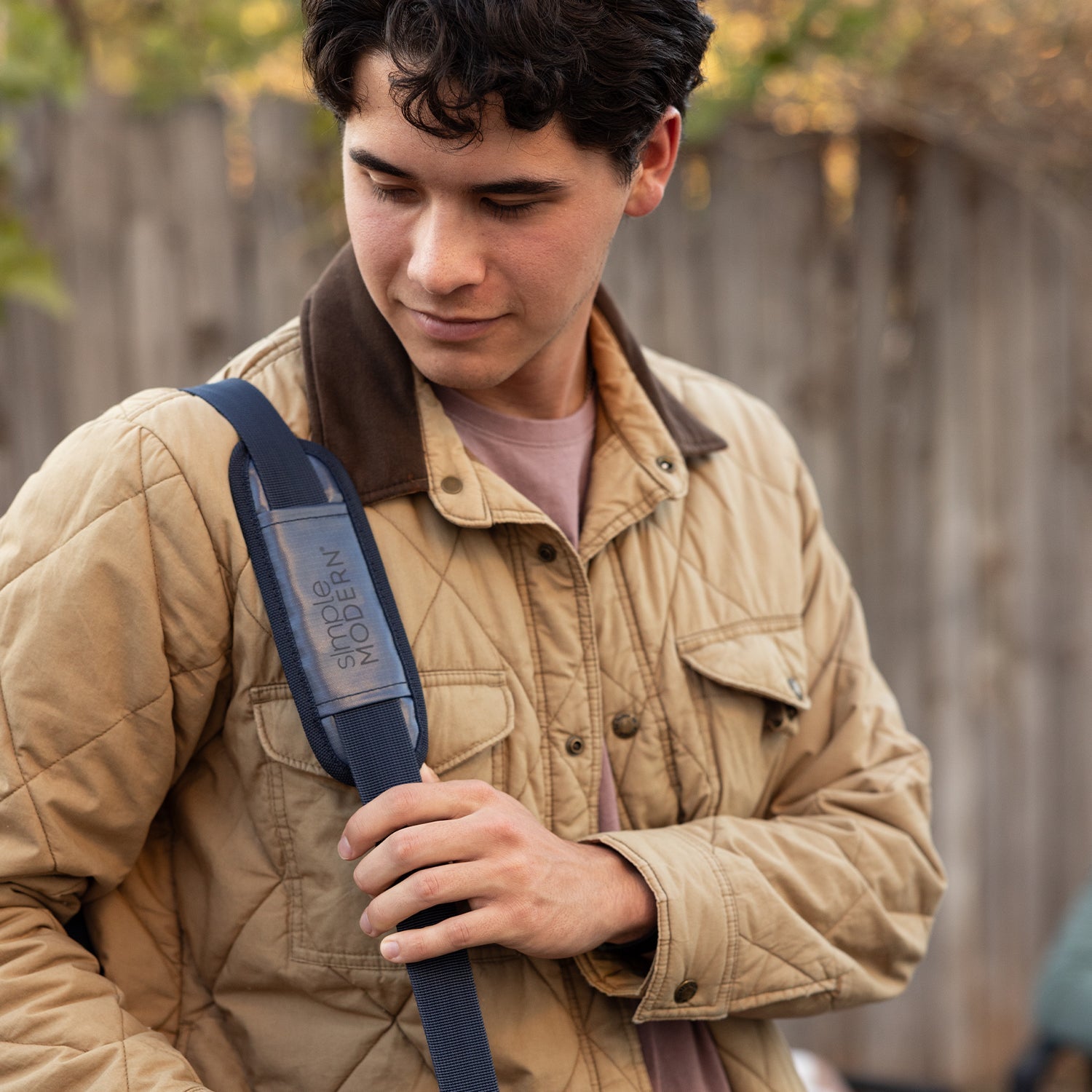 Person wearing tan quilted jacket with mauve accents against khaki and beige background, warm earthy tones throughout