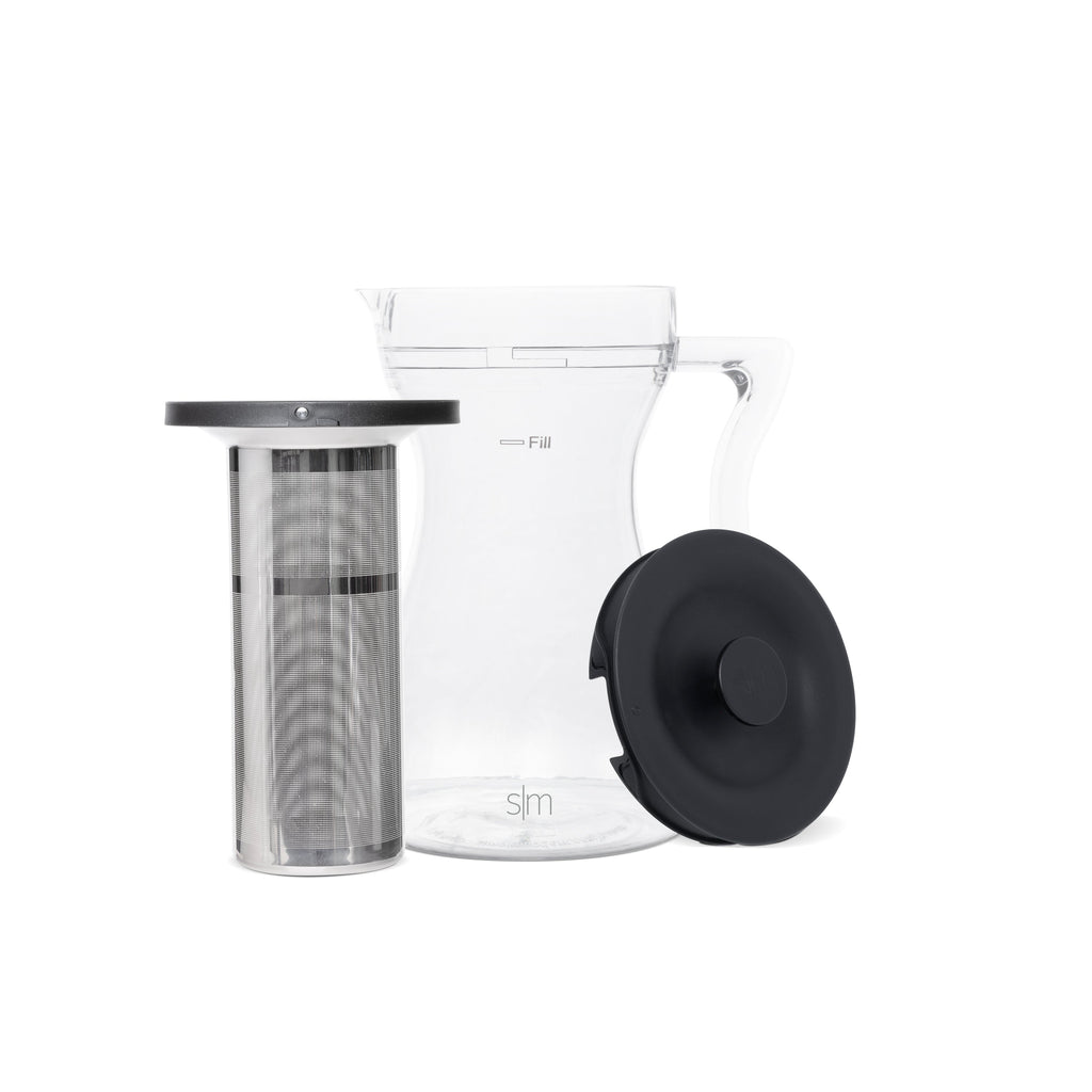 Exploded view of clear glass container with black metal components and lid on light gray background